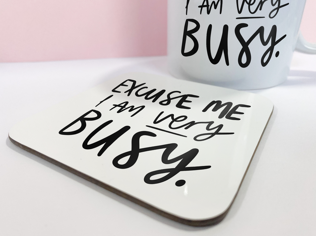 An 11oz ceramic mug reading "Excuse Me I Am Very Busy" with a matching coaster